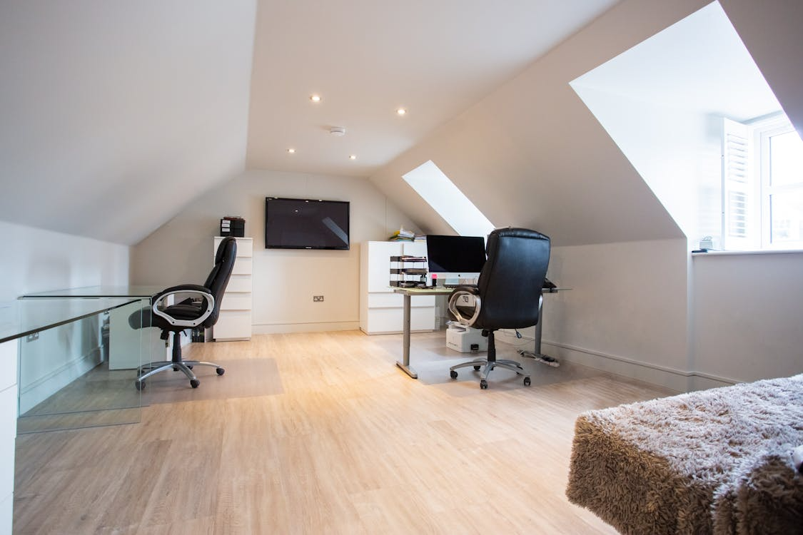attic conversion ideas showing renovated attic home office with skylights and sloped ceilings